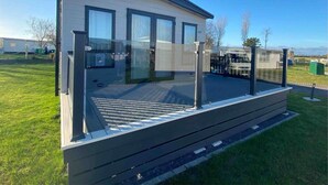 Ein modernes Mobilheim mit Balkon, großen Fenstern und einer flachen Dachkonstruktion.