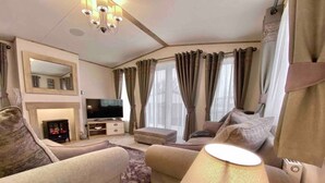 Ein modernes Wohnzimmer mit Flachbildfernseher, einer Couch, einem Couchtisch und einer Lampe.