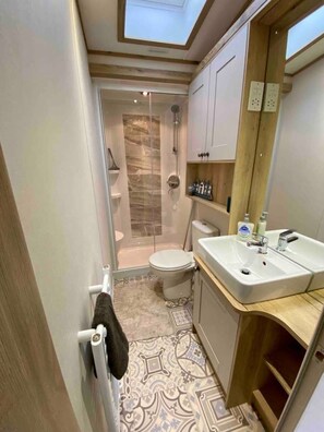 A compact bathroom with a shower, toilet, and sink.