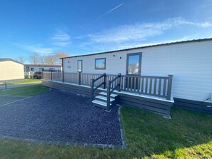 A mobile home with a front deck and steps leading to a front door.