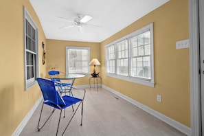 Relax in this serene space with a high ceiling, ceiling fan, and natural light pouring in through the window.