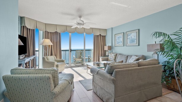 A spacious living room with a balcony, furnished with sofas and armchairs, and a television. - Luxury oceanfront resort-workout room, indoor/outdoor pools, lazy river, kids' pool-in Ocean Drive (North Myrtle Beach)