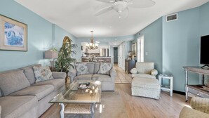 A living room with a sofa, armchair, and coffee table, a television, and a plant. - Luxury oceanfront resort-workout room, indoor/outdoor pools, lazy river, kids' pool-in Ocean Drive (North Myrtle Beach)