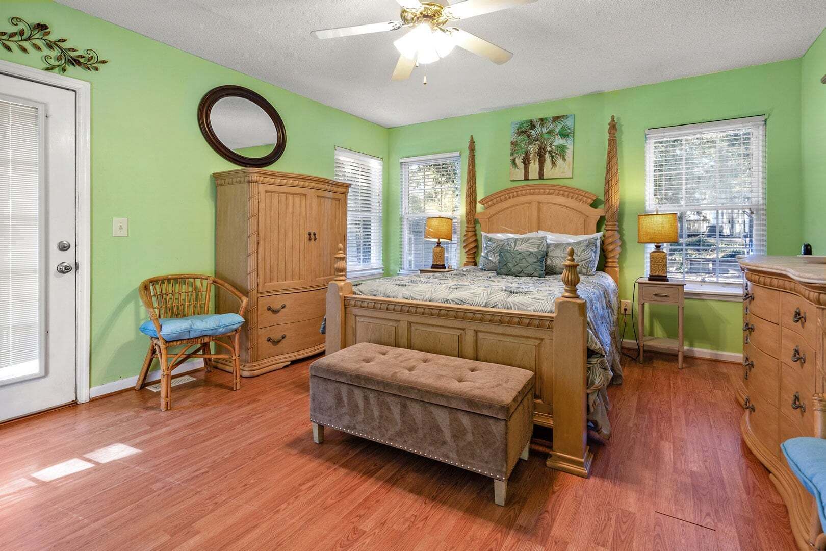 Une chambre à coucher avec un lit, une armoire en bois, un banc, une chaise et une fenêtre avec des stores.