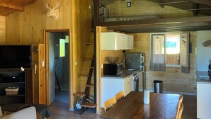 A wooden interior with a dining table, sofa, kitchen area, and a staircase. - Chalet du Moulin des fontaines near the Pont du Gard (Saint-Paul-les-Fonts)