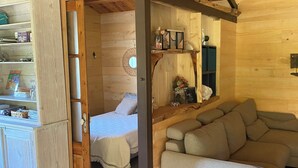 A cozy cabin interior with a wooden ceiling, a bed, a sofa, and a dining table. - Chalet du Moulin des fontaines near the Pont du Gard (Saint-Paul-les-Fonts)