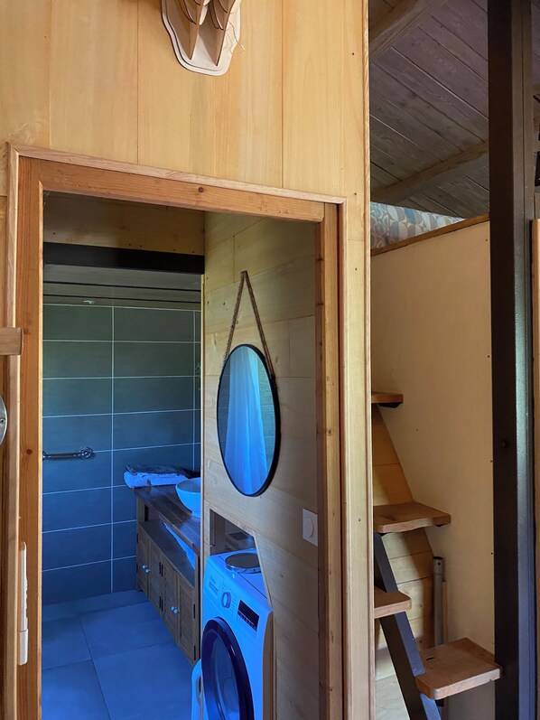 A wooden interior with a washing machine, a mirror, and a tiled wall.