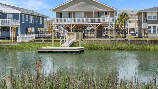 Een pand aan het water met een steiger, een overdekt terras en een twee verdiepingen tellend huis met balkon.
