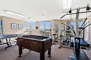 A gym with a foosball table, treadmills, and exercise equipment.