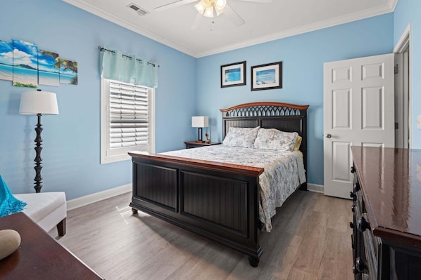 A bedroom with a bed, a nightstand, a lamp, a window with blinds, and a door.