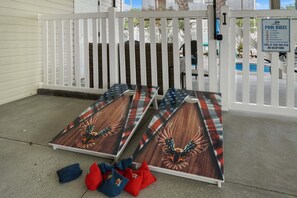 A pool area with a white fence, a pool rules sign, and a wooden deck with a flag design. - Private Pool Cottage | Marsh Views | 2 Blocks to Beach | EV Charger | Sleeps 8 (North Myrtle Beach)
