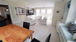 A spacious living room with a wooden dining table, striped armchairs, and a white sofa. - Ideal Madison home just steps to the beach (Madison)