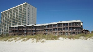 A beachfront hotel with multiple floors, balconies, and a sandy beach in the foreground. - Upscale family resort w/all the amenities-large pool, tennis courts, hot tub and more (North Myrtle Beach)