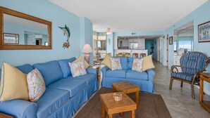A living room with two blue sofas, a wooden coffee table, and a wicker chair.