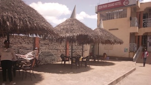 A hotel with thatched umbrellas, a stone wall, and a sign for the Gem Park Grand Hotel. - Gempark Grand Hotel (Thika)