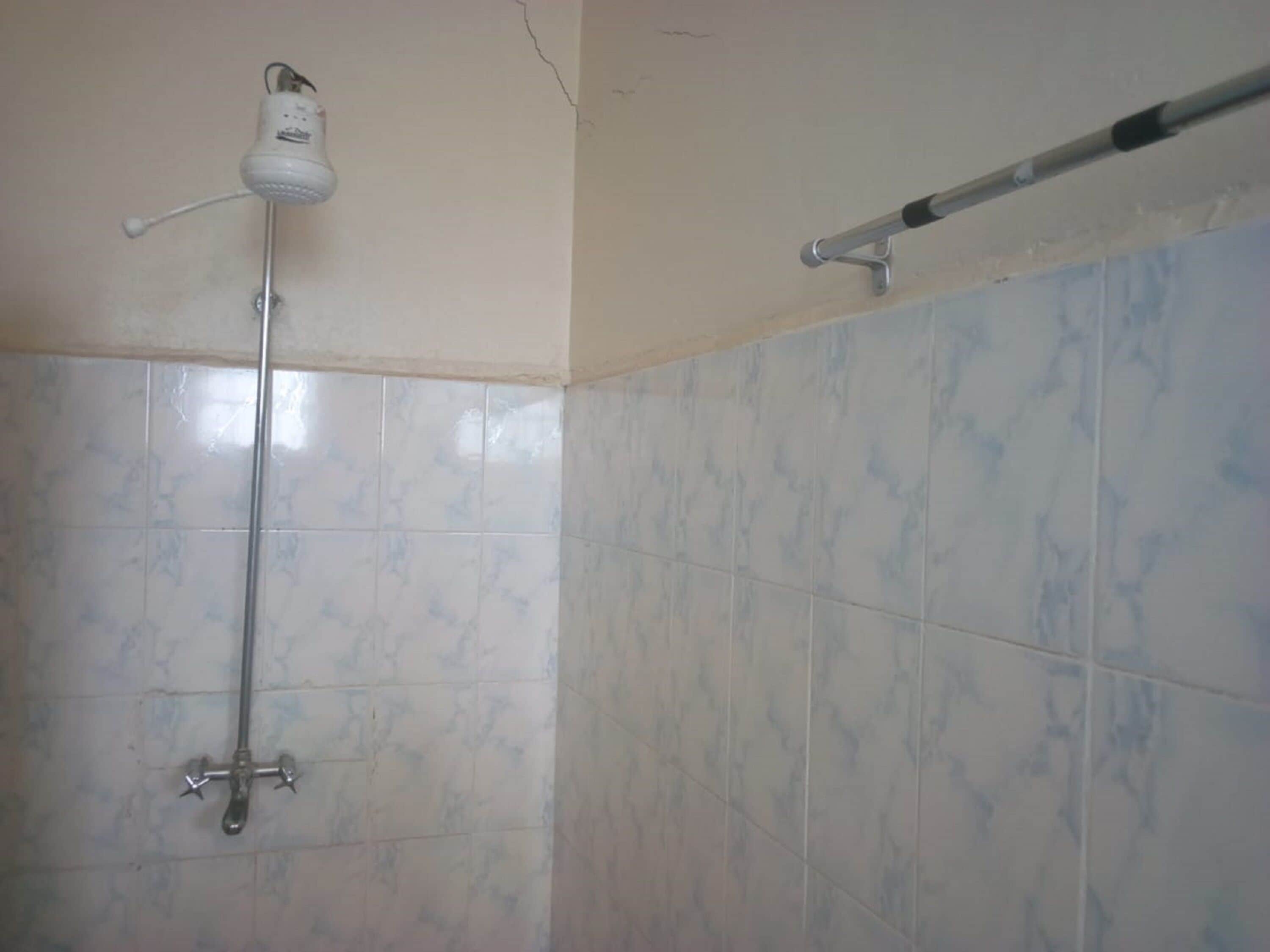 Een badkamer met een douche, betegelde wanden en een plafondlamp.