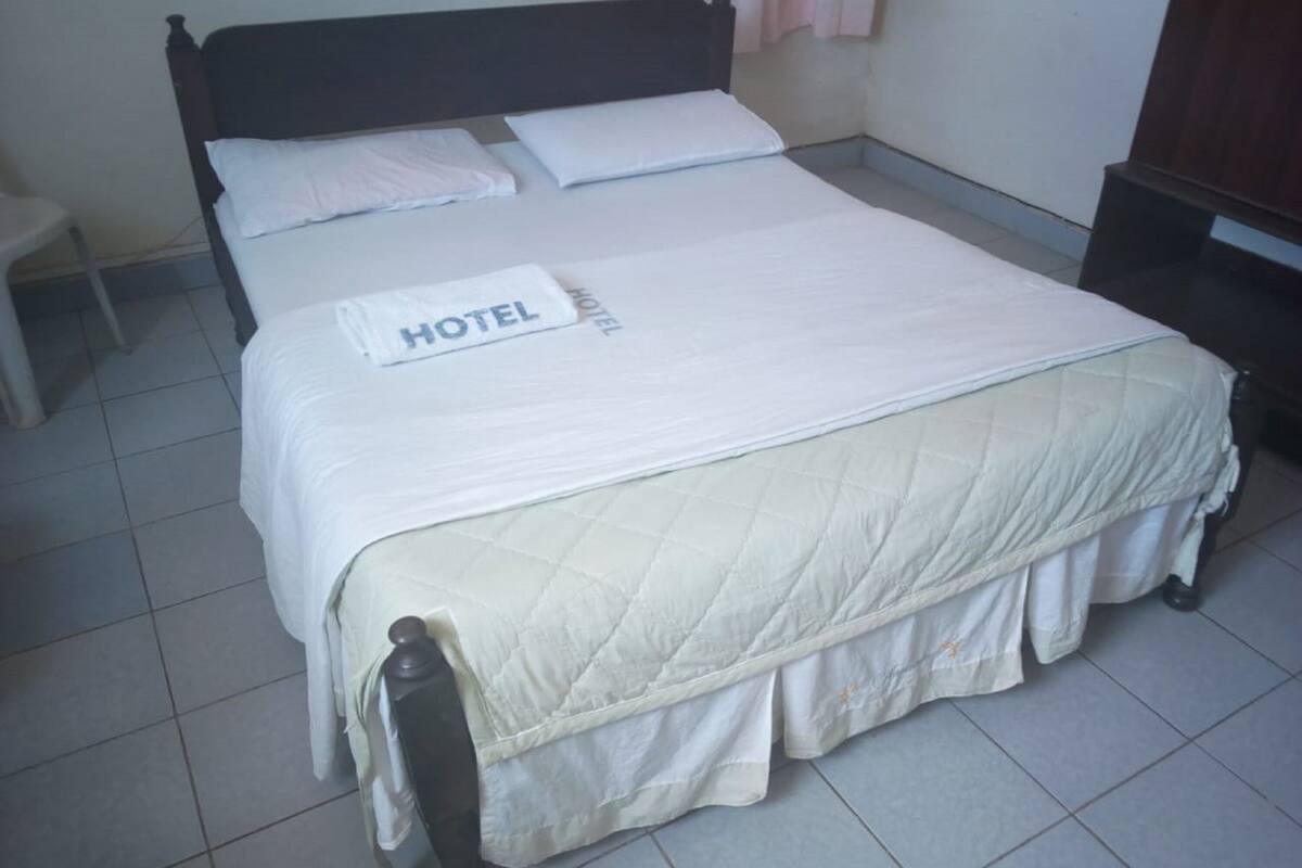 Una cama bien hecha con una colcha blanca y una almohada que dice 'HOTEL'.