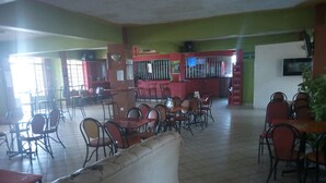 A spacious indoor seating area with multiple tables and chairs, a counter, and a tiled floor. - Gempark Grand Hotel (Thika)