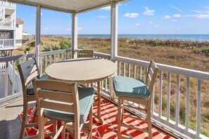 Enjoy a tranquil ocean view from this outdoor seating area with a round table and two chairs.