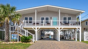 A two-story building with a balcony, a covered entrance, and a sign for 'Pelican's Perch' and 'Thommas'. - Channel home w/gorgeous saltwater pool, relaxing porches-fish, swim, sunbathe, enjoy! (North Myrtle Beach)