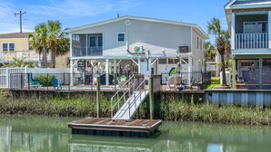A waterfront house with a dock, a covered porch, and a pool area. - Channel home w/gorgeous saltwater pool, relaxing porches-fish, swim, sunbathe, enjoy! (North Myrtle Beach)