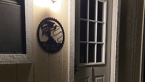 Pared exterior de madera con una puerta y un accesorio de iluminación.
