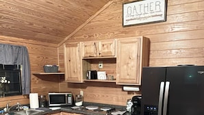 Una cocina con armarios de madera, un refrigerador negro, un microondas y un tostador.
