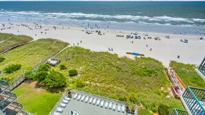 A beach with a wooden walkway leading to a grassy area with lounge chairs and a pool. - Perfect for families or groups looking for an upscale beachfront experience. (North Myrtle Beach)