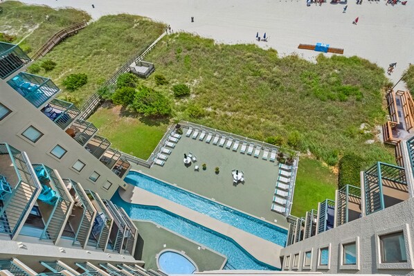 Un hotel de gran altura con piscina en la azotea, zona de playa y un paseo marítimo.