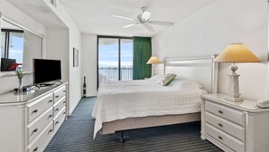 A hotel room with a bed, a desk, a TV, a lamp, and a view of the ocean. - Perfect for families or groups looking for an upscale beachfront experience. (North Myrtle Beach)