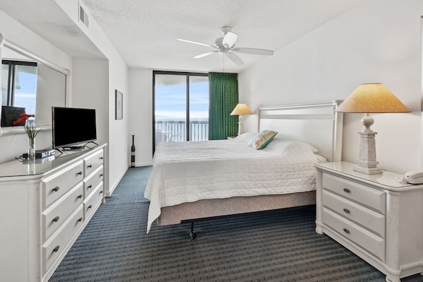 Ein Hotelzimmer mit Bett, Schreibtisch, Fernseher, Lampe und Meerblick.