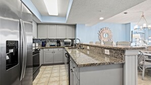 Una cocina moderna con armarios grises, electrodomésticos de acero inoxidable, encimera de granito y un espejo decorativo.