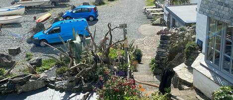 A coastal village with a gravel parking area, boats, and a row of houses with a pub named "The Five Pickets Inn".