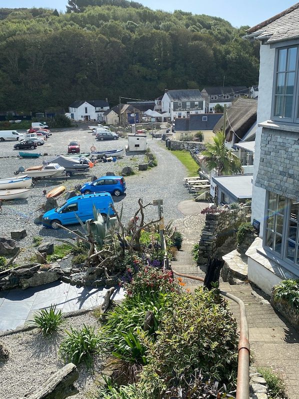 A coastal village with a gravel parking area, boats, and a row of houses with a pub named "The Five Pickets Inn".