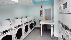 A laundry facility with multiple washing machines, a table, and a chair. - Spacious oceanfront condos w/pool and sundeck-walking distance to Cherry Grove Pier (North Myrtle Beach)