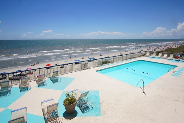A pool area with a view of the beach and ocean.