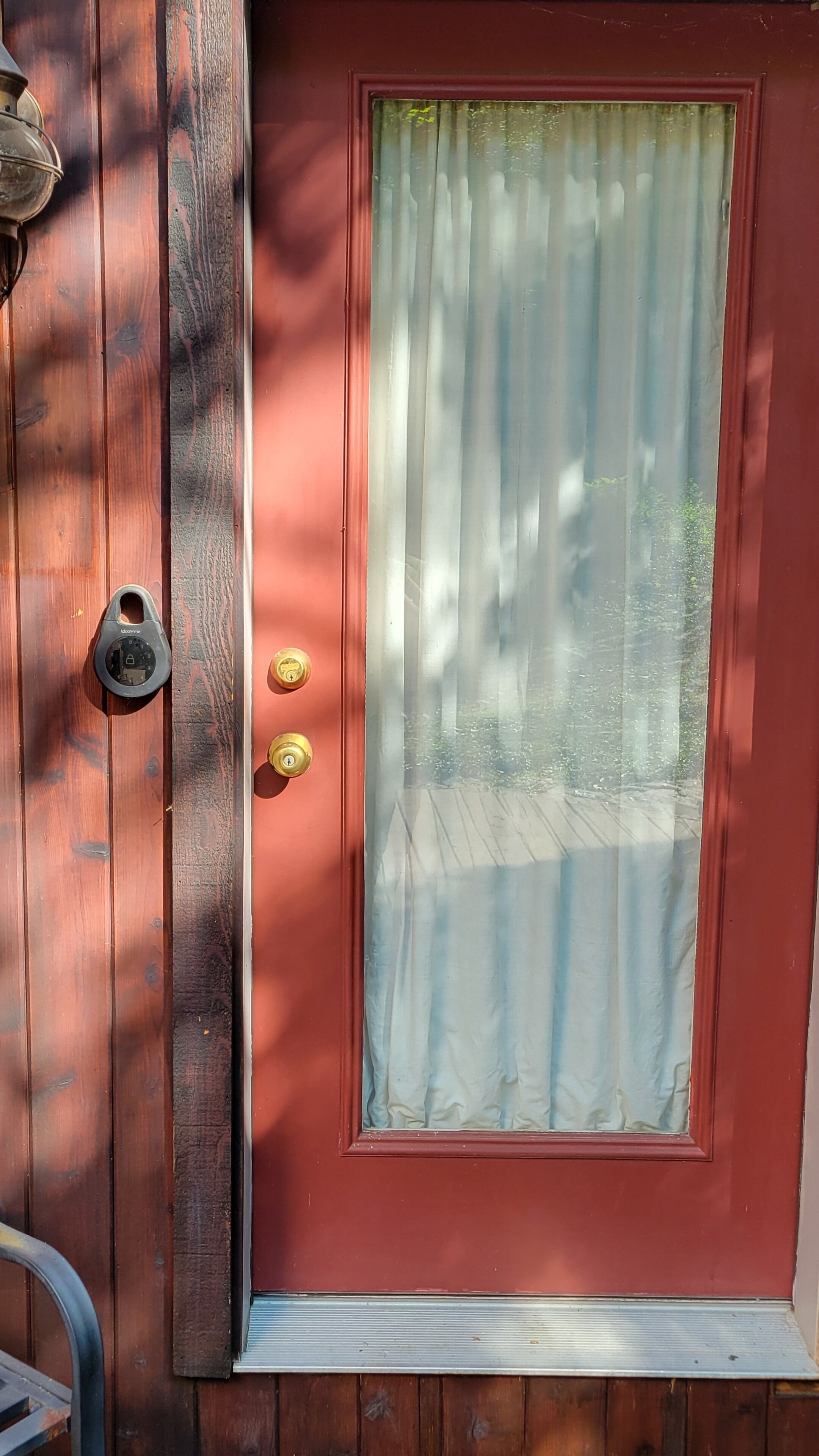 A red door with a glass panel and a brass door knocker.
