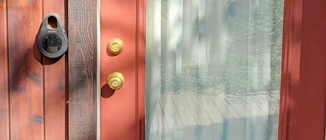 A red door with a glass panel and a brass door knocker.