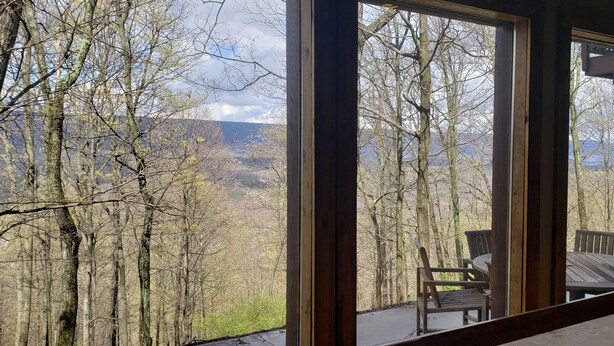 Ein Zimmer mit großen Fenstern und Blick auf bewaldetes Gelände sowie Berge.