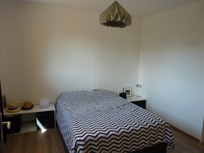 Et soveværelse med en seng, et natbord, et vægur og en loftlampe.