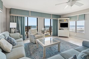A living room with a sofa, armchair, coffee table, and a TV stand. - Luxury oceanfront condo w/4th floor sundeck, pool, kids' pool in North Myrtle Beach (North Myrtle Beach)