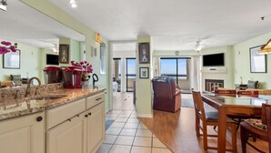 A spacious kitchen with a large island, a dining area with a wooden table and chairs, and a view of the ocean through the windows. - Great oceanfront view, big balcony, & condo resort with pool & hot tub in popular Cherry Grove Beach (North Myrtle Beach)