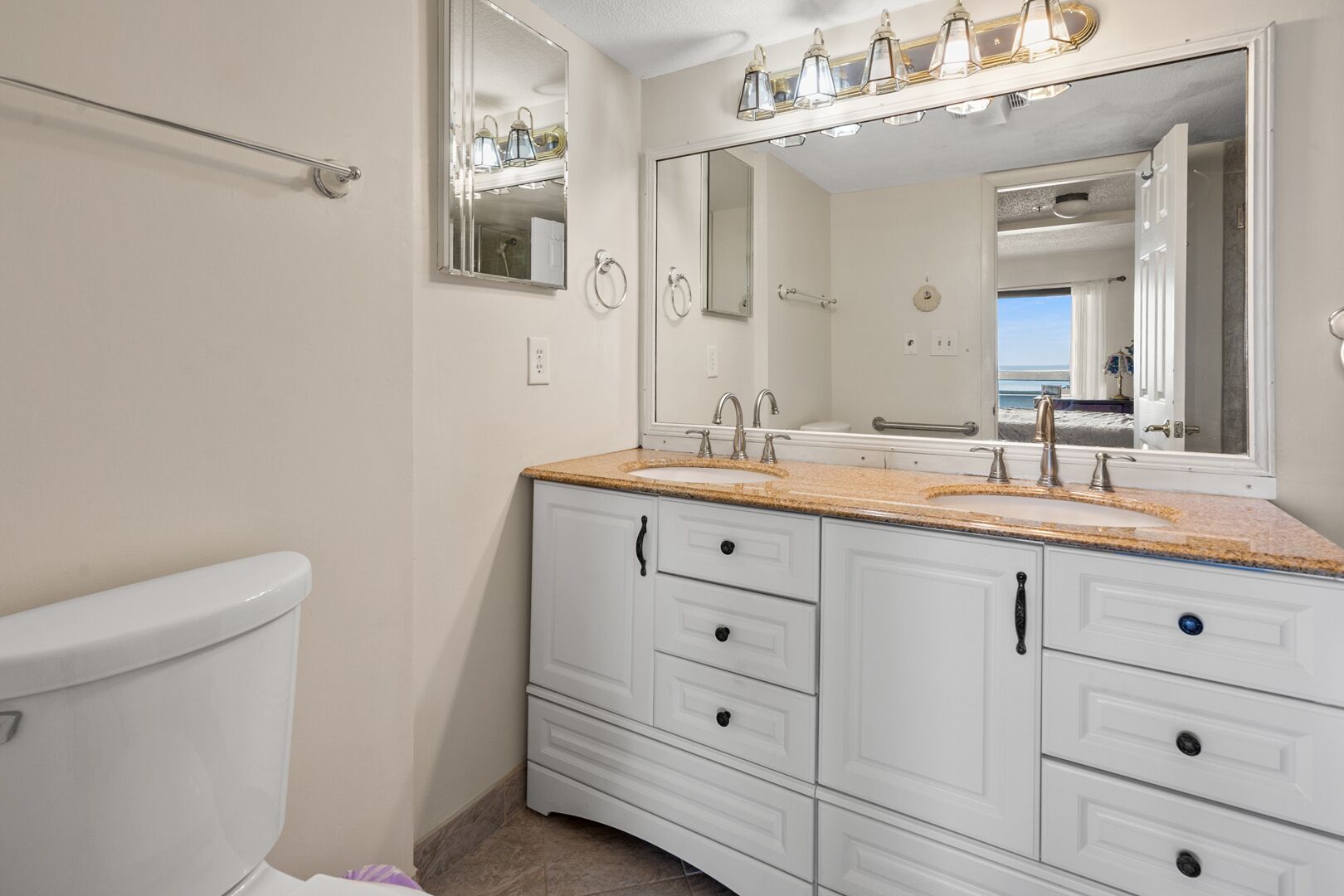 Une salle de bain comprenant des toilettes, un lavabo avec un miroir au-dessus et un meuble-lavabo avec des tiroirs.