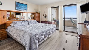 A bedroom with a large bed, wooden furniture, a TV, and a balcony with a view. - Great oceanfront view, big balcony, & condo resort with pool & hot tub in popular Cherry Grove Beach (North Myrtle Beach)