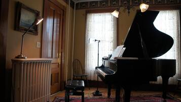 A room with a grand piano, a radiator, a chair, and a rug.