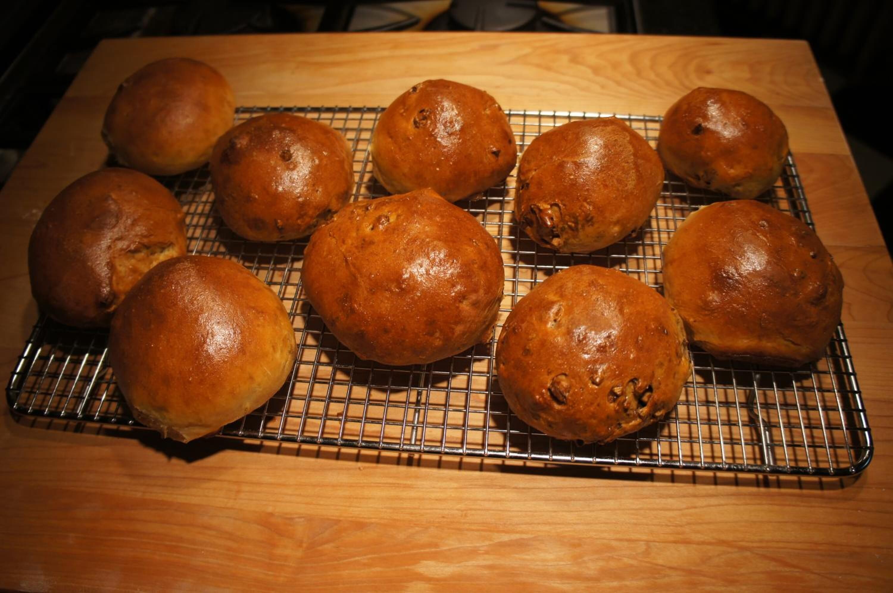 A cooling rack with several round baked goods on a wooden surface.