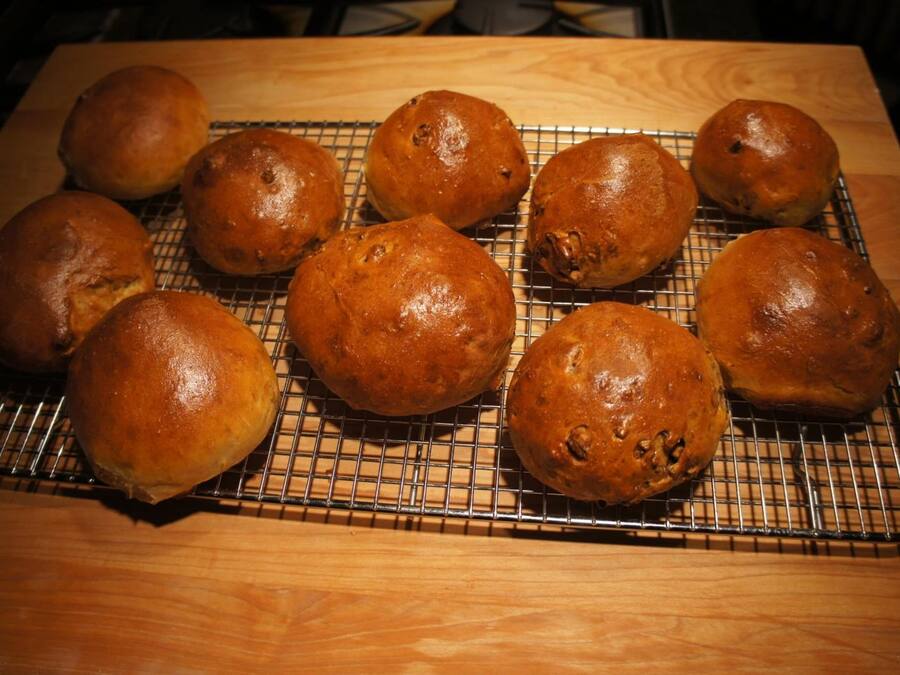 A cooling rack with several round baked goods on a wooden surface.