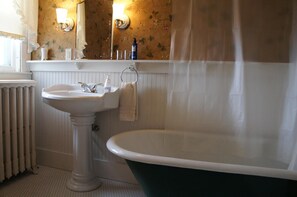 A bathroom with a freestanding bathtub, a pedestal sink, and a mirror above the sink. - Maplecroft Bed & Breakfast (Barre)