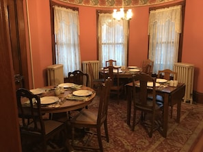 A dining room with a round table set for four, surrounded by wooden chairs. - Maplecroft Bed & Breakfast (Barre)