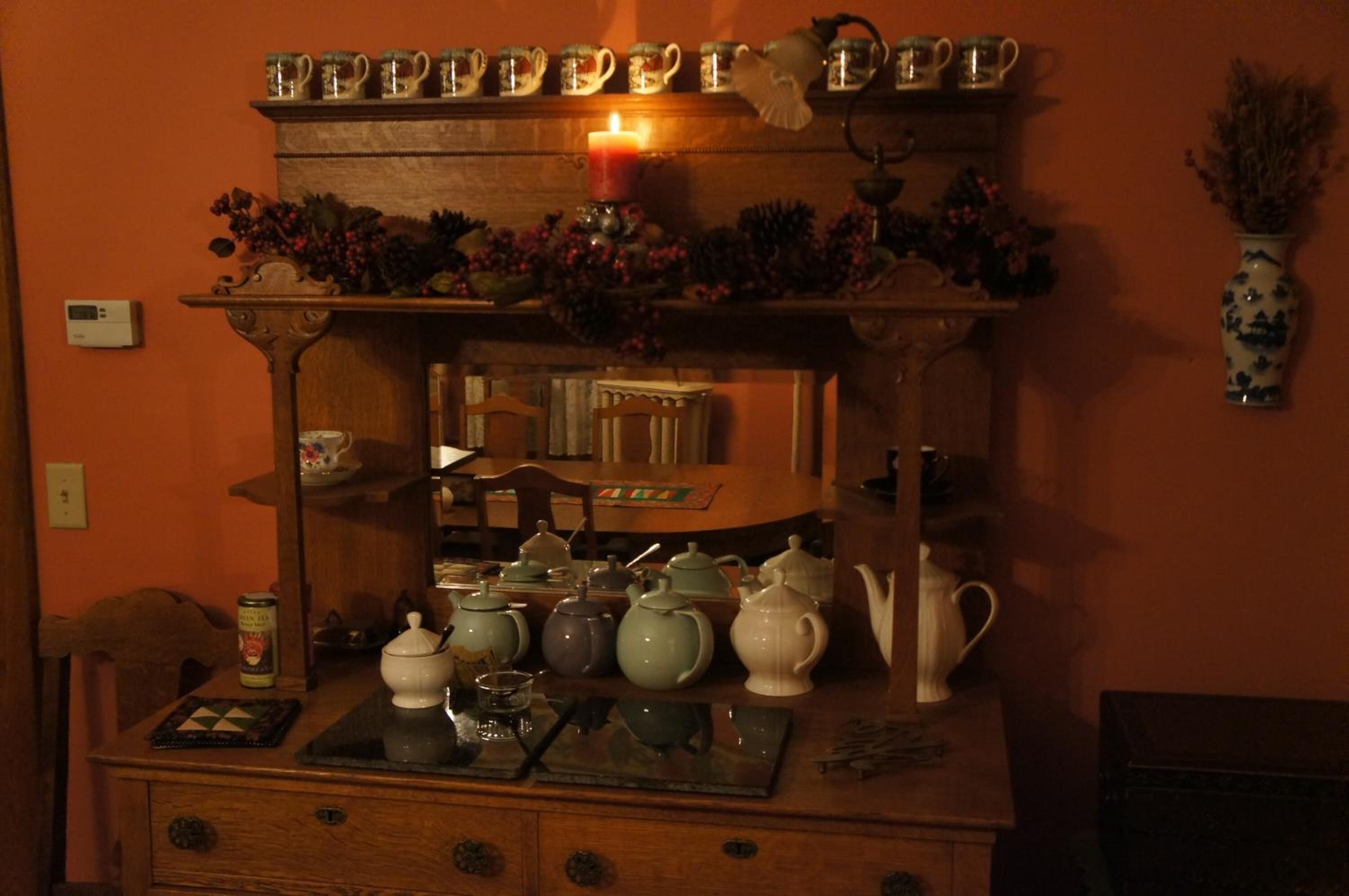 A wooden table with various kitchen items like teapots, cups, and a candle.